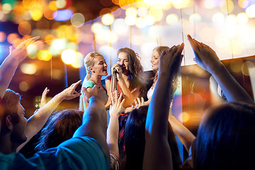 Image showing happy young women singing karaoke in night club