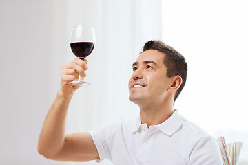 Image showing happy man drinking red wine from glass at home