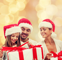 Image showing happy family in santa helper hats with gift boxes