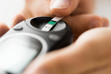 Image showing close up of man checking blood sugar by glucometer