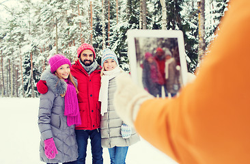 Image showing smiling friends with tablet pc in winter forest