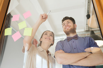 Image showing happy creative team writing on blank office glass