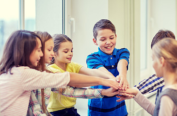 Image showing group of smiling school kids putting hands on top