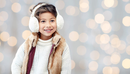 Image showing happy little girl in earmuffs over holidays lights