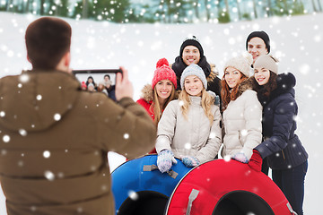 Image showing group of smiling friends with snow tubes