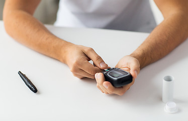 Image showing close up of man checking blood sugar by glucometer