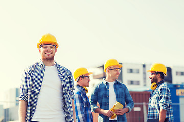 Image showing group of smiling builders in hardhats outdoors