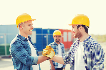 Image showing group of smiling builders in hardhats outdoors