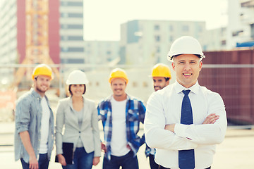 Image showing group of smiling builders in hardhats outdoors