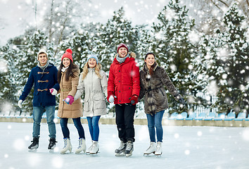 Image showing happy friends ice skating on rink outdoors