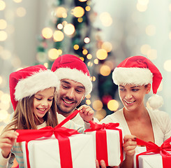 Image showing happy family in santa hats sitting with gift boxes