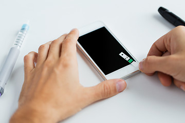 Image showing close up of man with smartphone making blood test