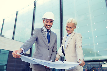 Image showing smiling businessmen with blueprint and helmets