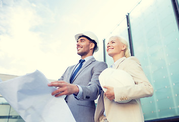 Image showing smiling businessmen with blueprint and helmets