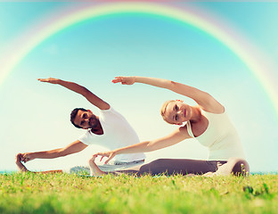 Image showing happy couple stretching and doing yoga exercises
