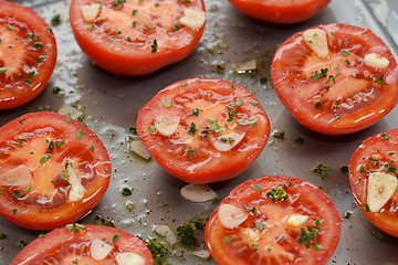 Image showing Tomato halves for ready roasting, with garlic, thyme and oil