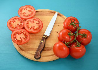 Image showing Tomatoes, whole and sliced with knife on wooden board