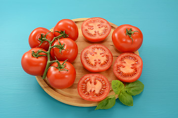 Image showing Tomatoes - cut, whole and on the vine with fresh basil