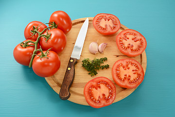 Image showing Tomatoes cut for roasting with knife, garlic and thyme