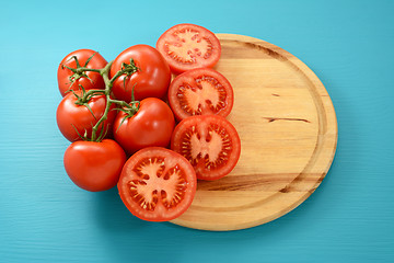 Image showing Vine tomatoes whole and halved on a circular board