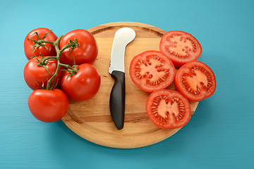 Image showing Cutting vine tomatoes with knife on wooden board