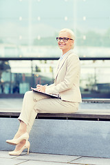 Image showing young smiling businesswoman with notepad outdoors