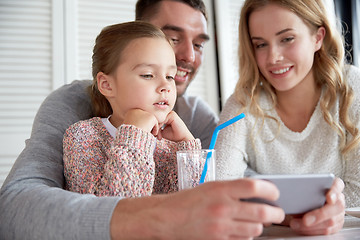 Image showing happy family with smartphone at restaurant