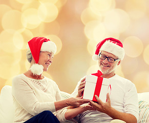 Image showing happy senior couple in santa hats with gift box