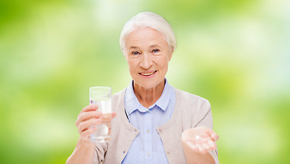 Image showing happy senior woman with water and medicine