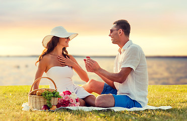 Image showing smiling couple with small red gift box on picnic