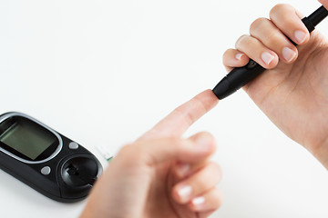 Image showing close up of woman making blood test by glucometer