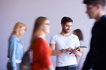 Image showing student working on tablet, people group passing by