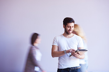 Image showing student working on tablet, people group passing by