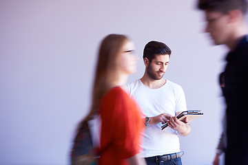 Image showing student working on tablet, people group passing by