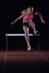 Image showing woman athlete jumping over a hurdles