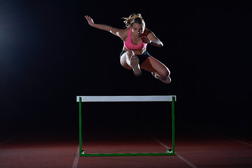 Image showing woman athlete jumping over a hurdles