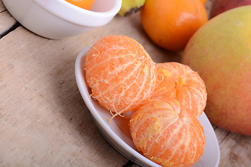 Image showing Bowls of slices mandarin with apple on rustic wooden background