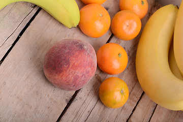 Image showing Bananas apple mandarin peach strawberry on wooden background as health food concept