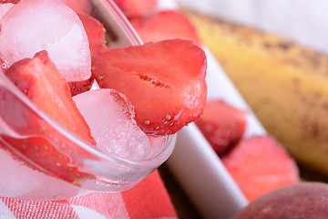 Image showing A slice of red strawberry on glass plate with bananas and peach, health food concept