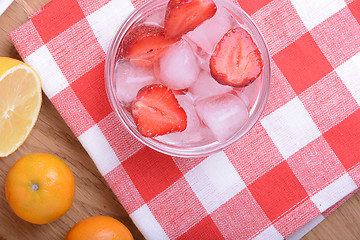 Image showing A slice of red strawberry on glass plate with lemon and mandarin in party theme background