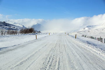 Image showing Snowy and icy road with volcanic mountains in wintertime