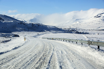 Image showing Snowy and icy road with volcanic mountains in wintertime