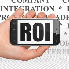 Image showing Finance concept: Hand Holding Smartphone with ROI on display