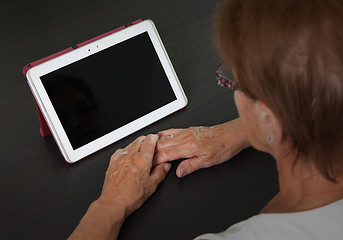 Image showing Senior lady relaxing and reading the screen of her tablet