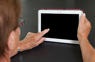 Image showing Senior lady relaxing and reading the screen of her tablet