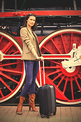 Image showing woman with luggage near the old steam locomotive