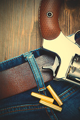 Image showing silvery revolver nagant with cartridges on old blue jeans