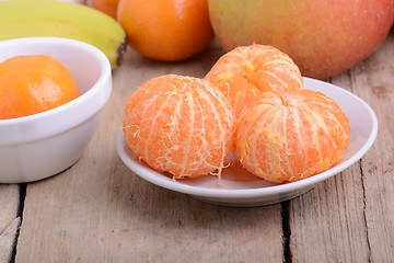 Image showing Bowls of slices mandarin with apple on rustic wooden background