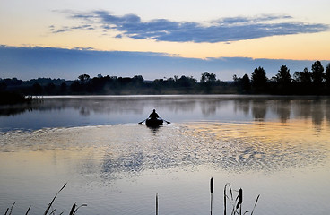 Image showing A fisherman in a boat sailing in the morning mist