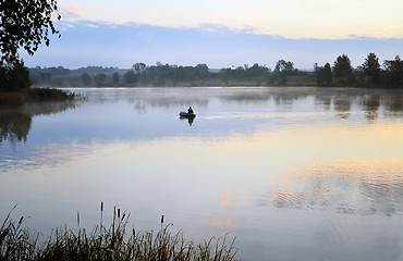 Image showing A fisherman in a boat sailing in the morning mist
